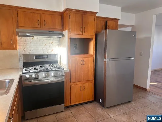 a kitchen with stainless steel appliances granite countertop a refrigerator and a stove