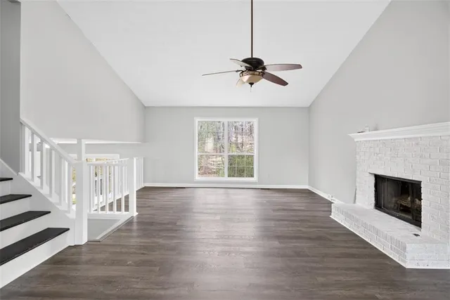 a view of an empty room with wooden floor fireplace and a window