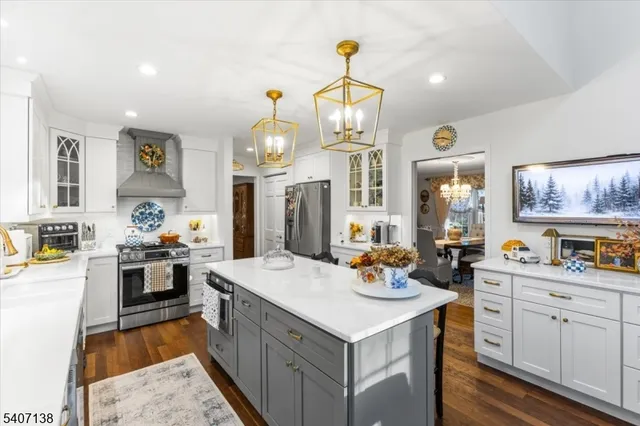 a large kitchen with kitchen island a stove a sink a refrigerator and a dining table with wooden floor