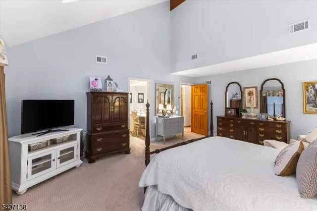 a bedroom with a bed and a flat tv screen on dresser