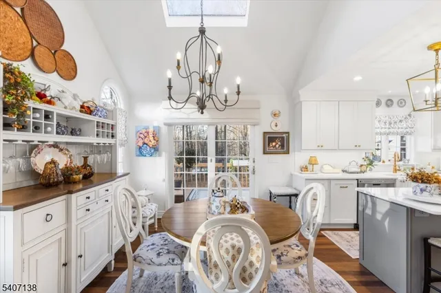 a very nice looking kitchen with granite countertop a stove a sink a dining table and chairs with wooden floor