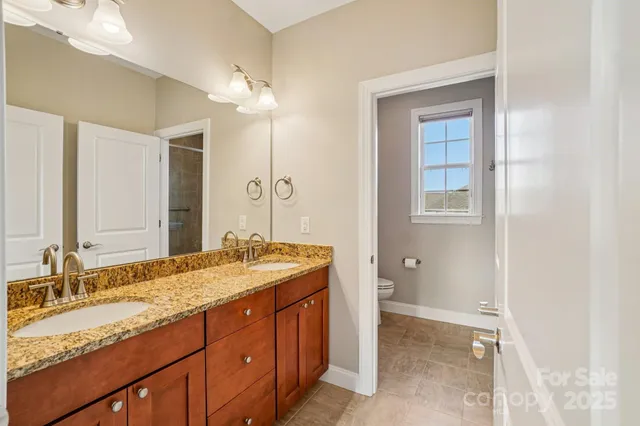 a bathroom with a granite countertop double vanity sink a mirror and a