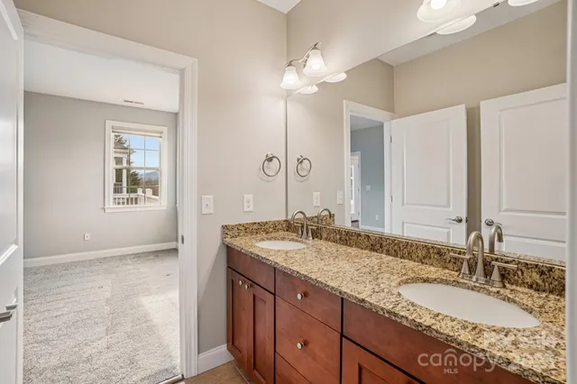 a bathroom with a granite countertop double vanity sink and a mirror