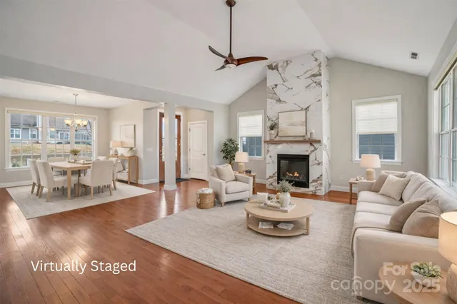 a living room with furniture a fireplace and a dining table with kitchen view