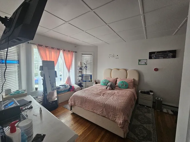 a bedroom with a bed wooden floor and window