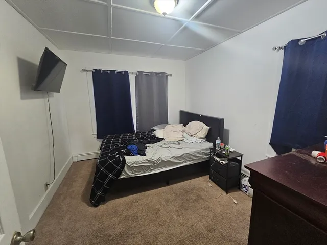 a living room with furniture a flat screen tv and a refrigerator