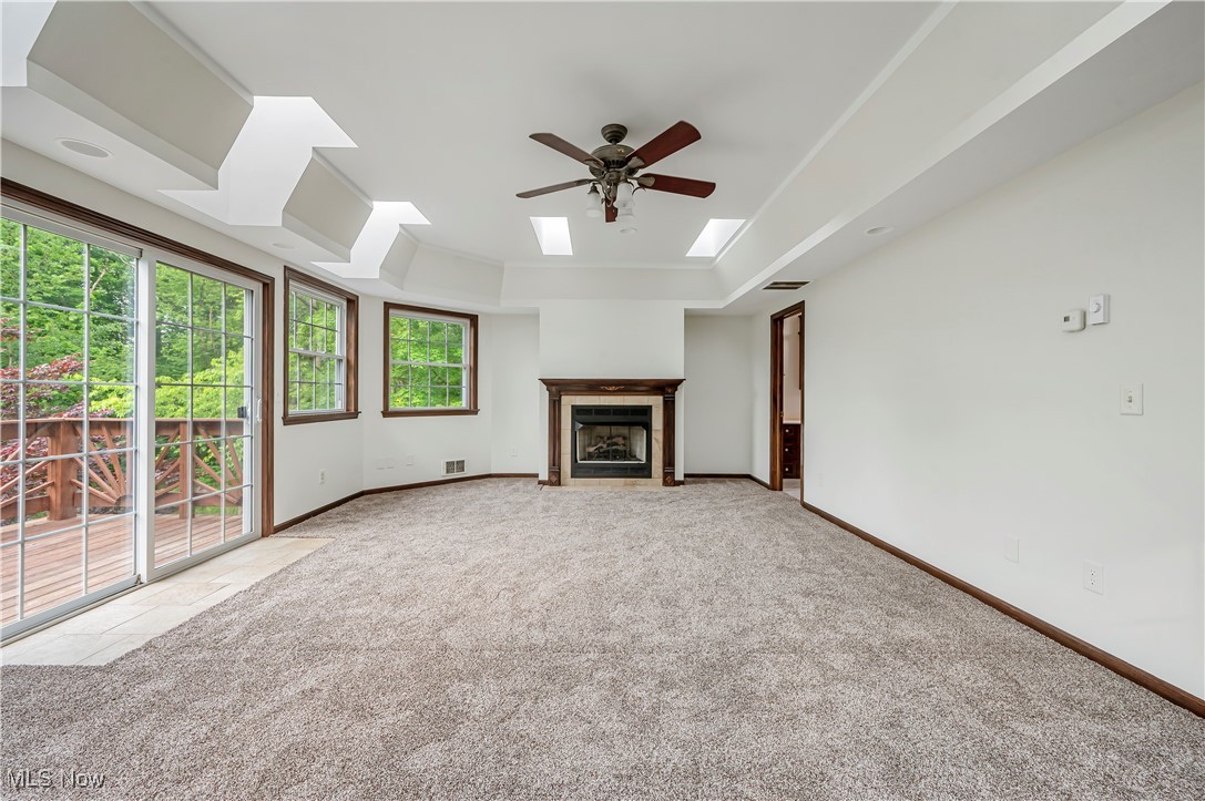 12358 Harmon Road New Springfield, OH 44443 - Photo 15 of 44 Unfurnished living room with a raised ceiling, a fireplace with flush hearth, light colored carpet, and a skylight