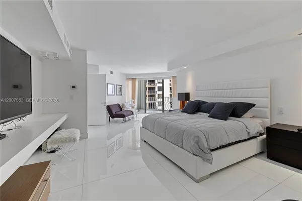 a spacious bedroom with a bed and a flat screen tv