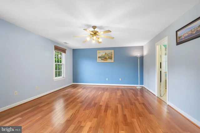 a view of an empty room with window and wooden floor