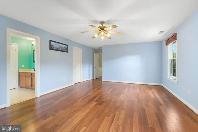a view of an empty room with window and wooden floor