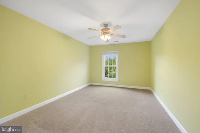 an empty room with a window and a ceiling fan