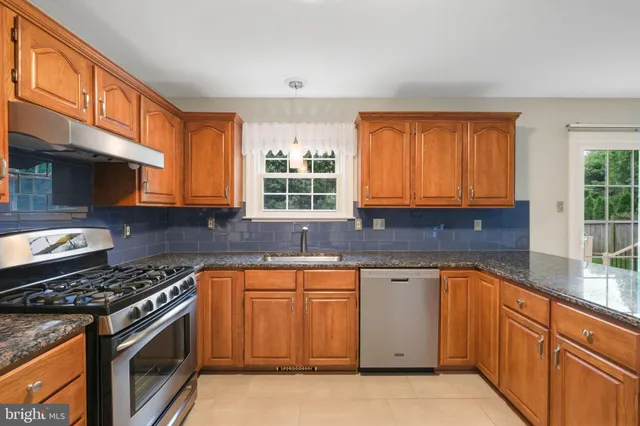 a kitchen with stainless steel appliances granite countertop a stove a sink and a microwave