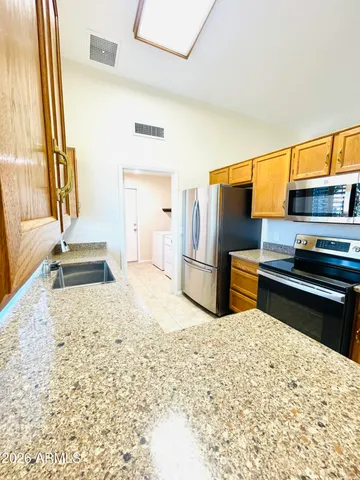 a kitchen with granite countertop a refrigerator and a sink