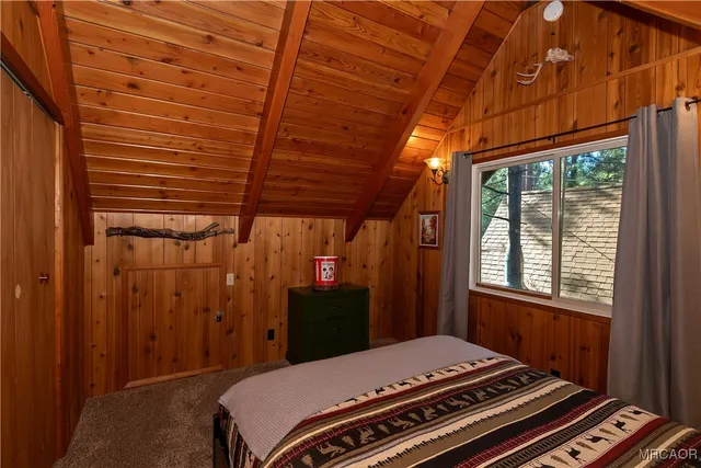 a bedroom with a bed a dresser next to a window