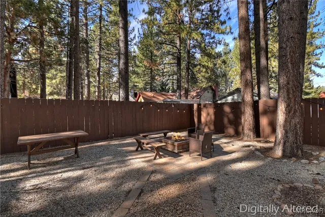a view of backyard with a table and chairs and a large tree
