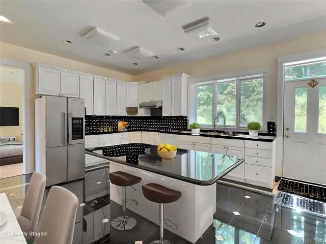 a kitchen with stainless steel appliances granite countertop a sink a stove a refrigerator cabinets and a dining table