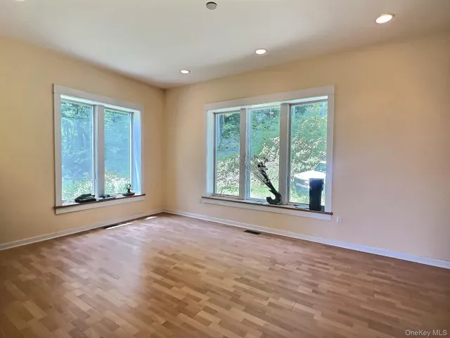 a view of an empty room with a window and wooden floor