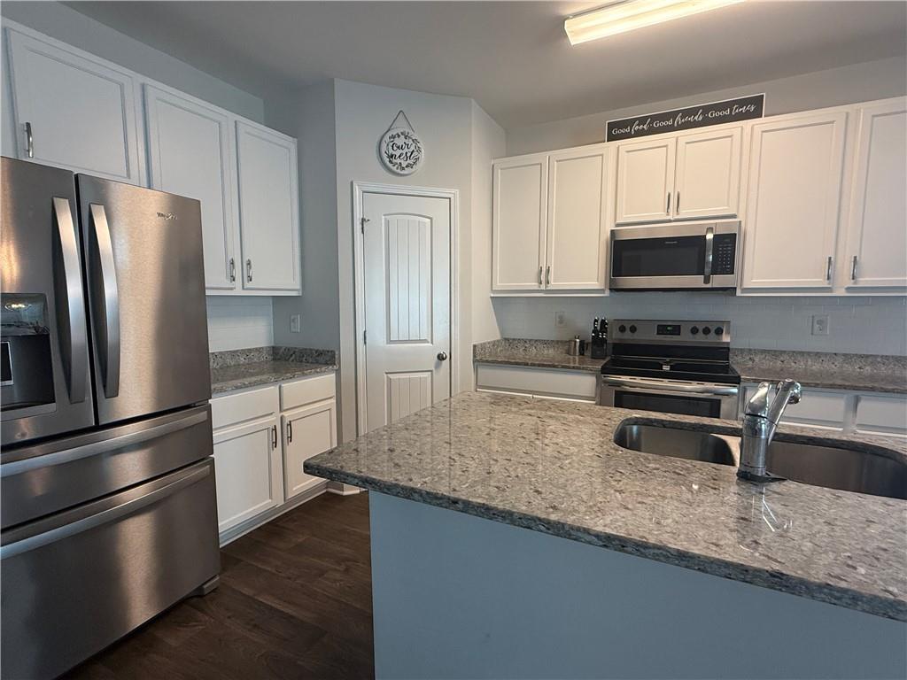 358 Mulberry Road Winder, GA 30680 - Photo 5 of 21 a kitchen with granite countertop a refrigerator stove and microwave