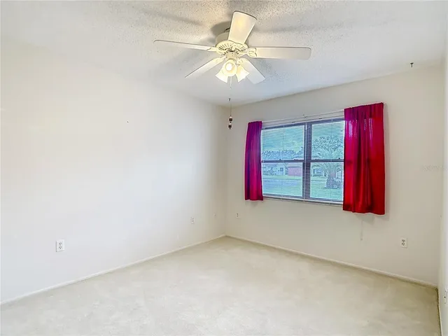 an empty room with a chandelier fan and closet