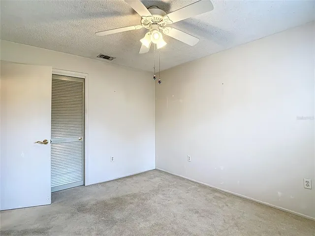 an empty room with a chandelier fan and windows
