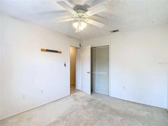 an empty room with windows and fan