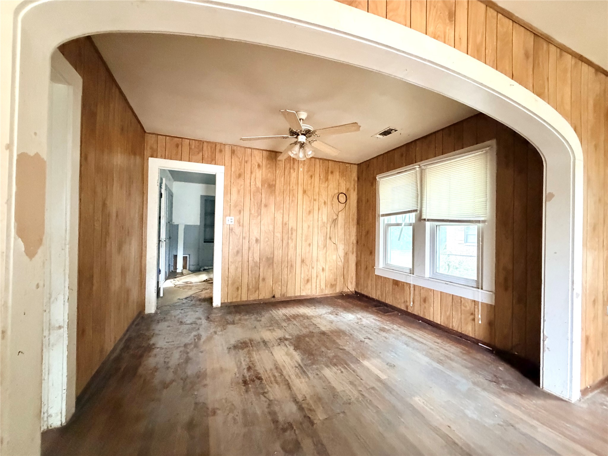 702 East 18th Street Cameron, TX 76520 - Photo 14 of 14 An open floorplan with hardwood flooring and paneling, ready for renovation.