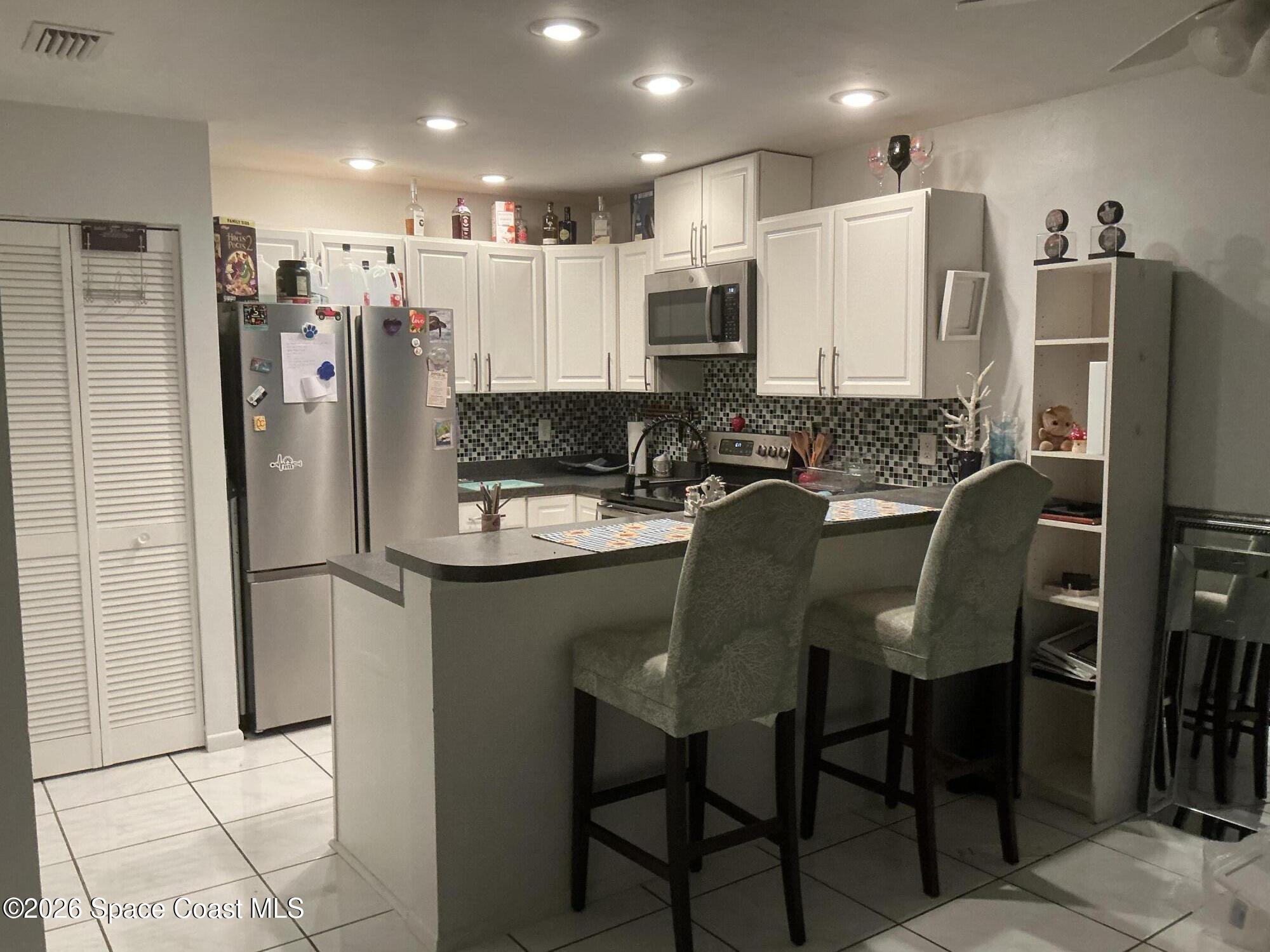 1470 Sheafe Avenue Northeast, Unit 106 Palm Bay, FL 32905 - Photo 5 of 16 a kitchen with stainless steel appliances granite countertop a refrigerator and a stove top oven