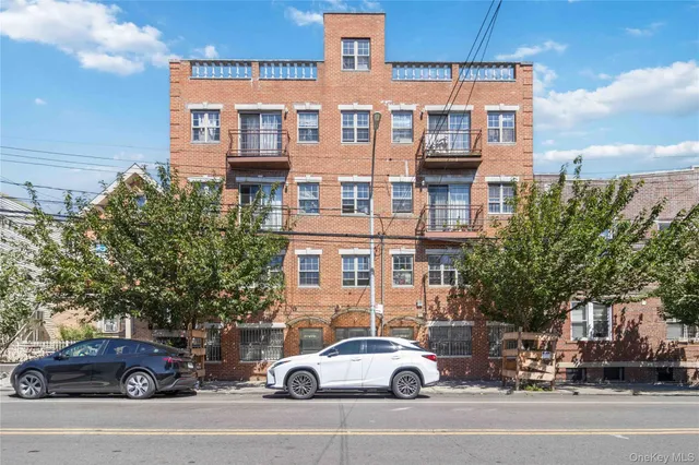 a front view of a building with lot of cars and trees
