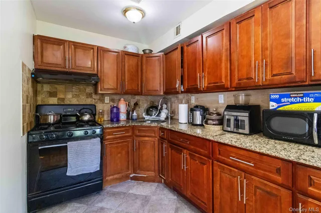 a kitchen with granite countertop stainless steel appliances a stove sink and cabinets
