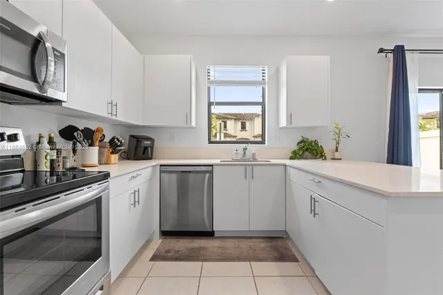 a kitchen with white cabinets and window