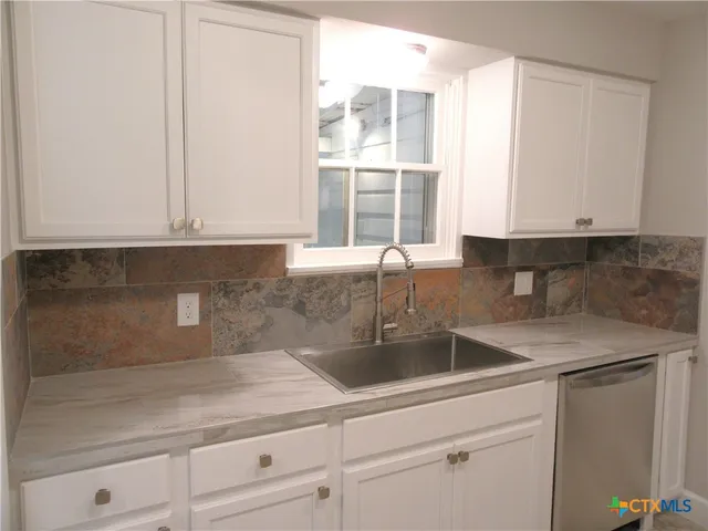 a kitchen with granite countertop white cabinets and window