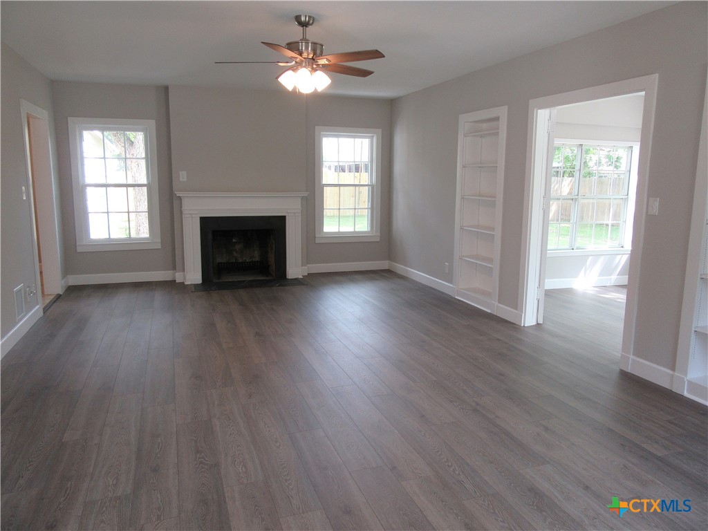 415 Easy Street Marlin, TX 76661 - Photo 6 of 45 an empty room with wooden floor fireplace and windows