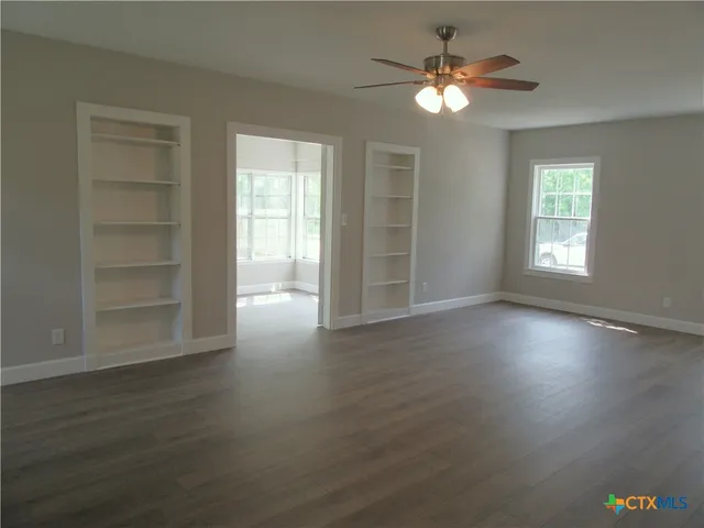 a view of an empty room with a window and wooden floor