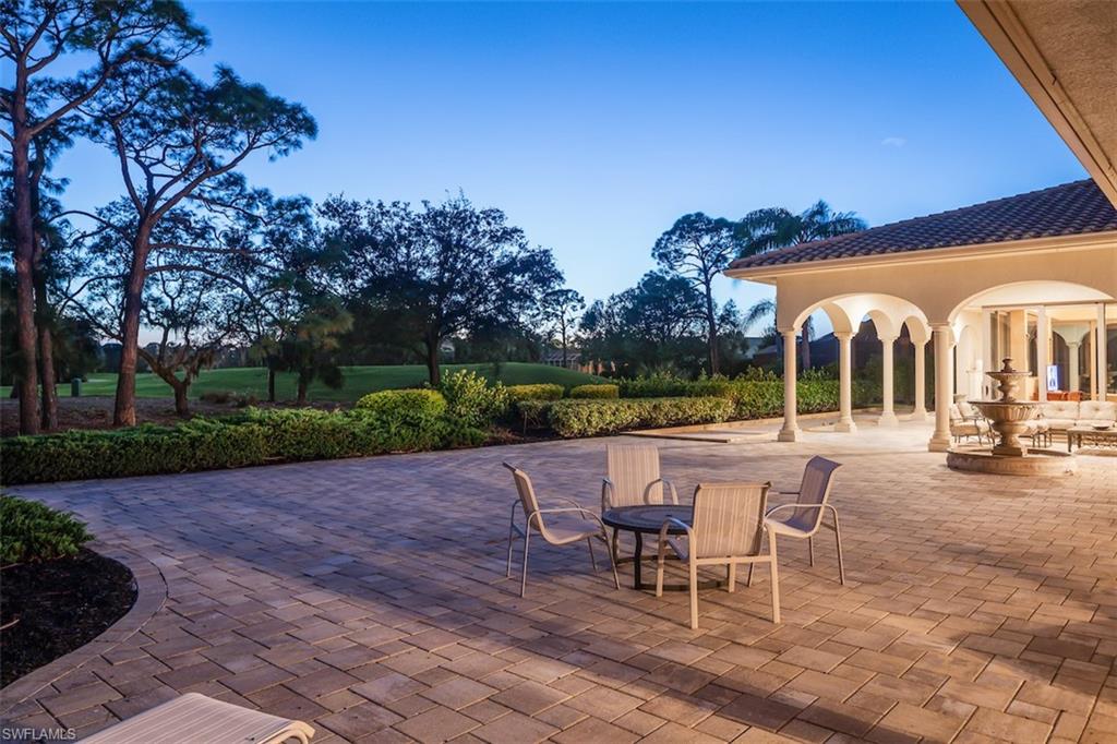 219 Cheshire Way Naples, FL 34110 - Photo 38 of 46 a view of a patio with a table and chairs under an umbrella with a garden