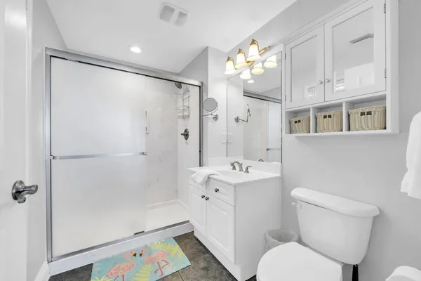 a bathroom with a sink a toilet a mirror a vanity and shower