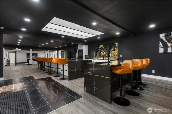 a large white kitchen with kitchen island a stove a sink a refrigerator and chairs