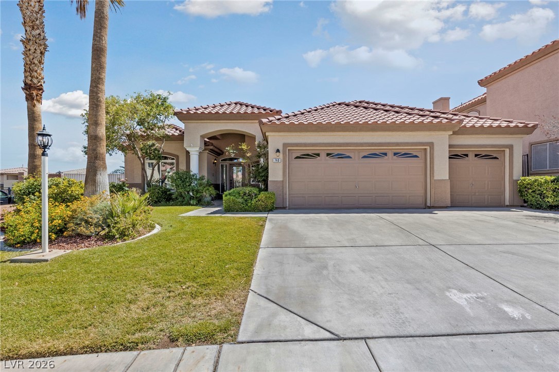 740 Aldo Rae Court, Unit NONE Henderson, NV 89052 - Photo 2 of 35 A terracotta-roofed residence presents a spacious driveway, welcoming green lawn, and integrated garages.