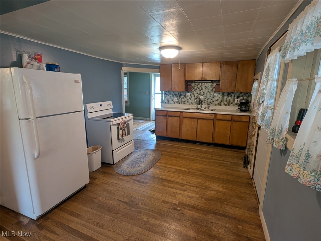 2356 Walter Main Road Geneva, OH 44041 - Photo 17 of 27 Kitchen with dark wood-style flooring, brown cabinets, a sink, light countertops, and white appliances