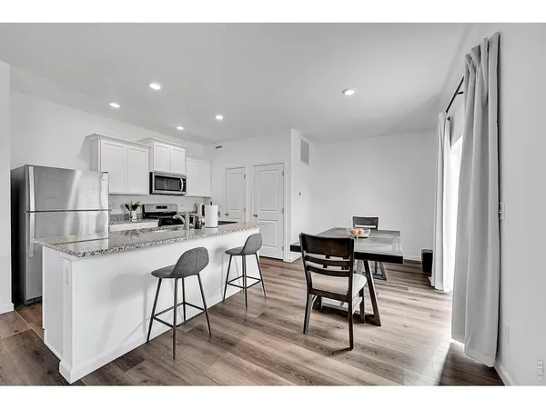 a kitchen with stainless steel appliances kitchen island granite countertop a table chairs microwave and sink
