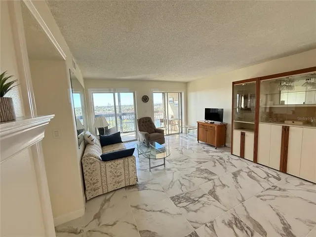 a living room with furniture a large window and stainless steel appliances