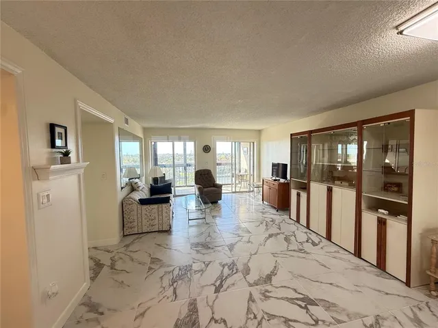 a kitchen with stainless steel appliances kitchen island granite countertop a refrigerator a stove a microwave oven with white cabinets and wooden floor