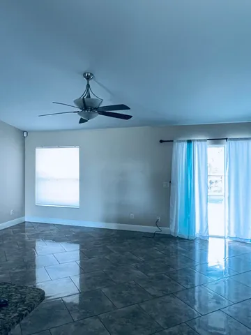 an empty room with windows and ceiling fan