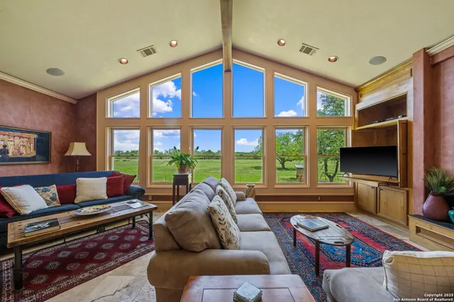 a living room with furniture a floor to ceiling window and a flat screen tv