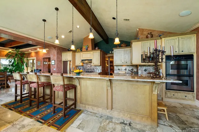 a open kitchen with stainless steel appliances granite countertop a stove top oven a refrigerator and chairs