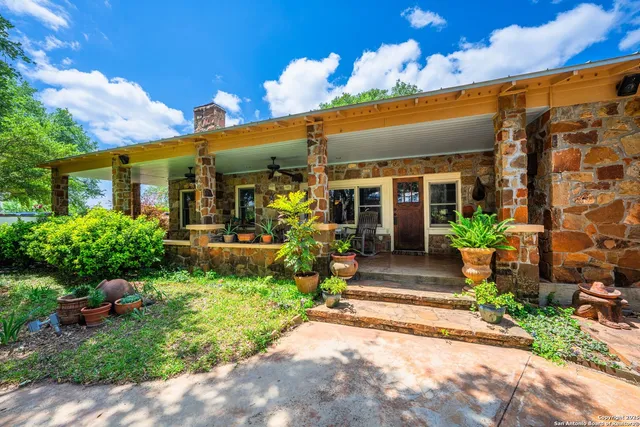 a view of a house with potted plants and a bench