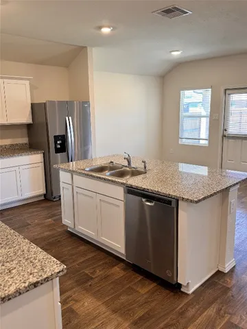 a kitchen with granite countertop a sink stove and refrigerator
