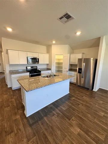 a view of a kitchen with kitchen island a sink wooden floor and a counter top space