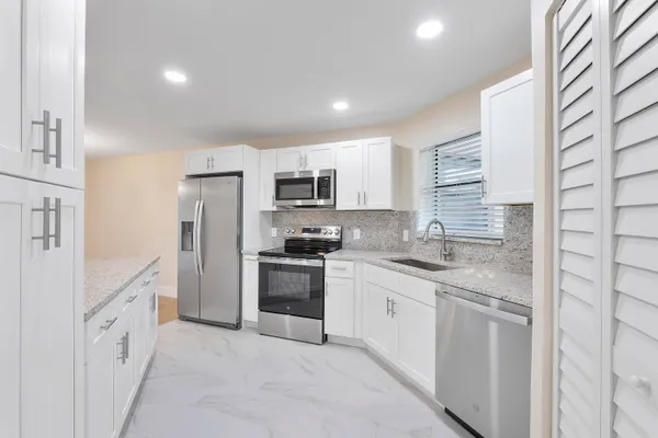 a kitchen with granite countertop a sink stove refrigerator and cabinets