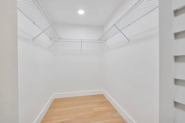 an empty room with wooden floor ceiling fan and windows