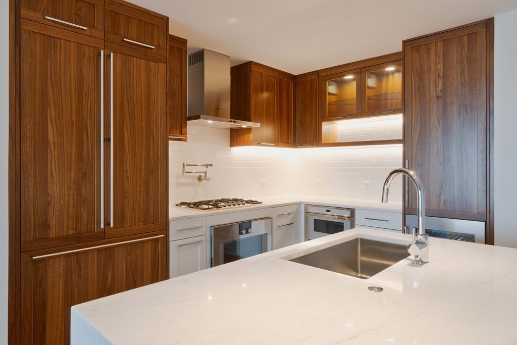 a kitchen with granite countertop a sink stainless steel appliances wooden floor and cabinets